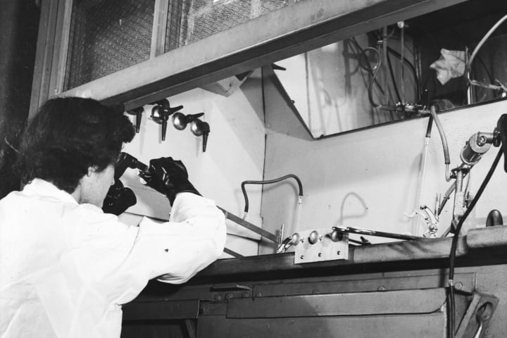 A technician at Brookhaven National Laboratories processes radioactive sodium using a remote control manipulator