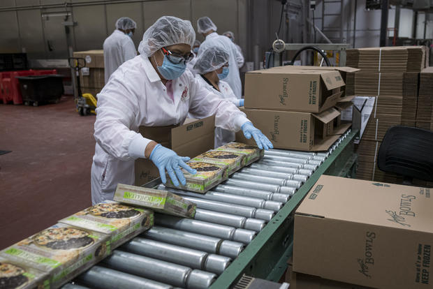 A worker wearing a protective mask and food processing clothing prepares packaged food bowls to be boxed at an Amy's Kitchen facility in Santa Rosa California, U.S., on Wednesday, June 24, 2020.