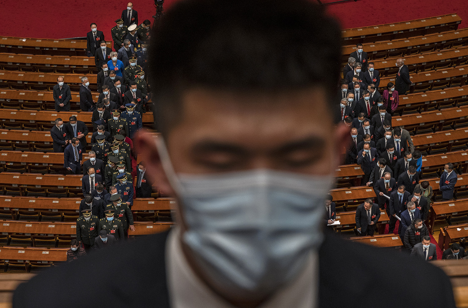 A security officer wears a mask as delegates leave the floor after the opening session of the Chinese Peoples Political Consultative Conference.