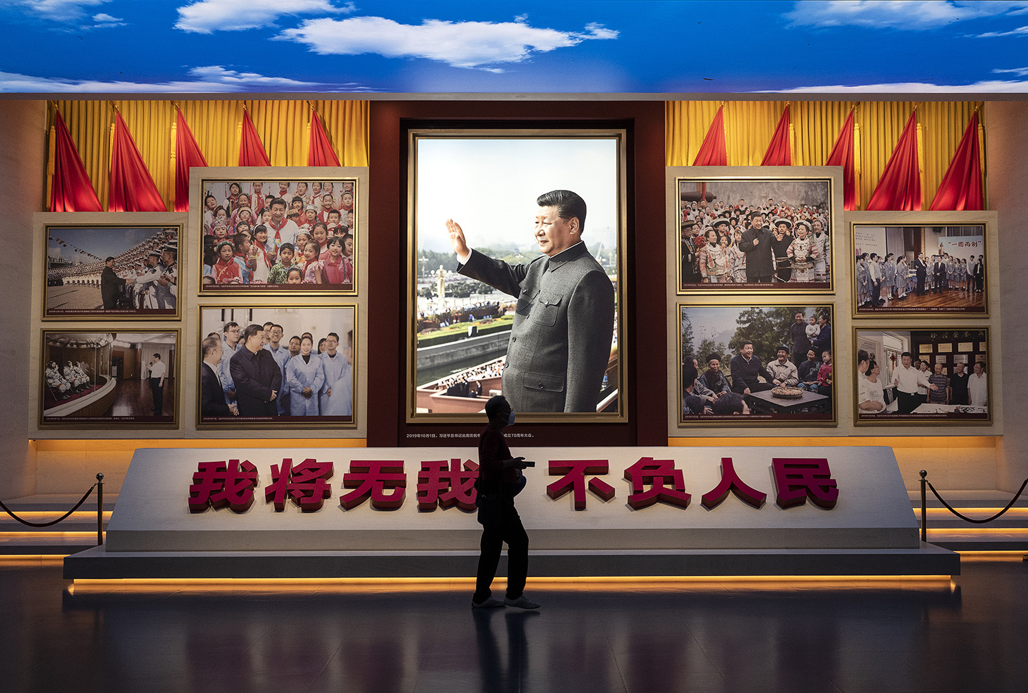 A visitor walks by a display showing images of Xi at the Museum of the Communist Party in Beijing.