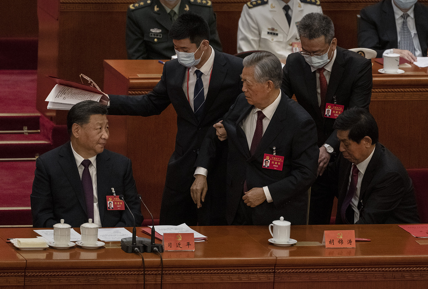 Xi Jinping looks at former President Hu Jintao as he is escorted out early from the closing session of the 20th National Congress of the Communist Party of China